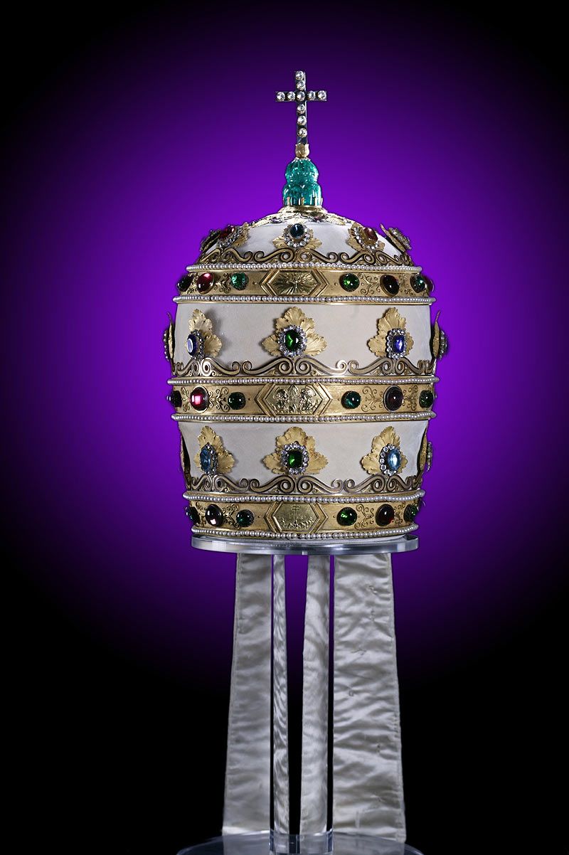 上图：拿破仑三重冕（Napoleon Tiara），是拿破仑于1805年送给教宗庇护七世的三重冕（Triregnum），虽然用珠宝装饰得非常华丽，却故意做得又小又重，难以佩戴。每道箍的中间原来都有一个美化拿破仑的浮雕，后来被圣经经文所取代：上层是徒二十28，中间是启十一4，底层是诗八十五10。 教宗本笃十五世卖掉头饰的珠宝为一战受难者筹款，代之以玻璃复制品。